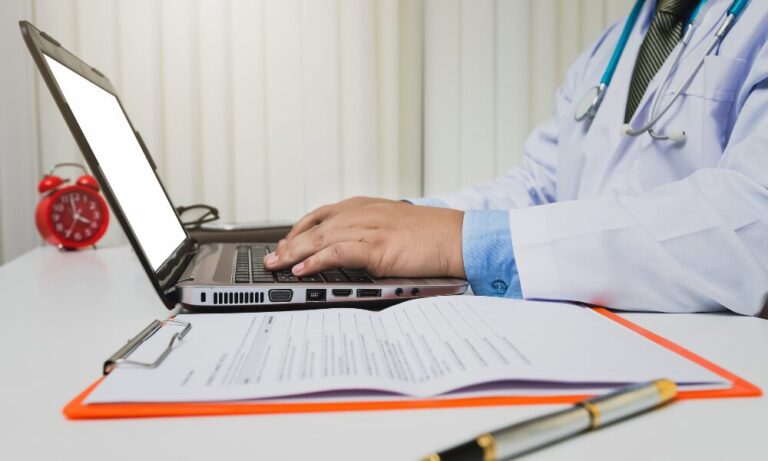 Researcher preparing a clinical trial protocol on a laptop, ensuring accurate documentation and regulatory compliance.